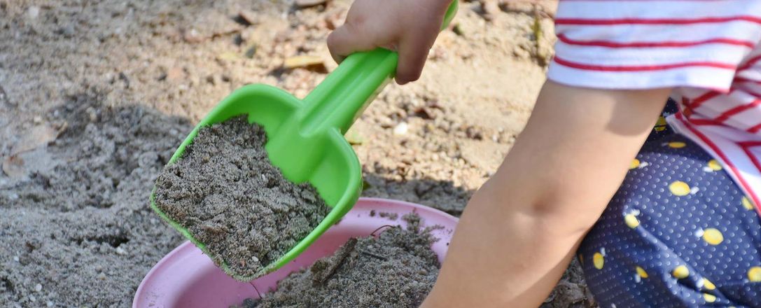 Ein Kind spielt im Sandkasten mit Eimer und Schaufel